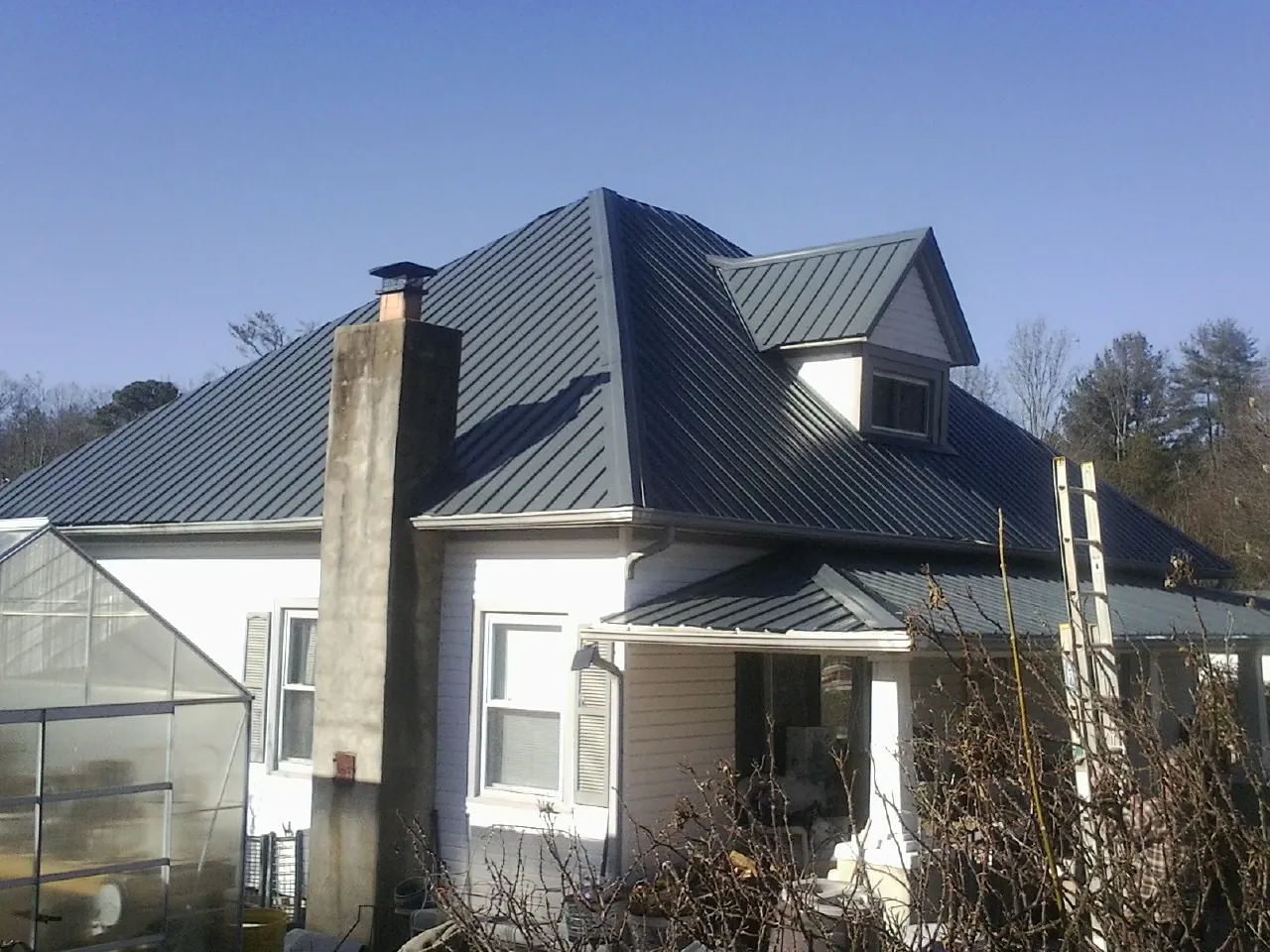 Dark blue standing seam metal roof on a white farmhouse with dormer — Slate & Tile Roof Repair by Roofing Brothers in Robesonia