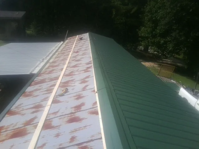 Old rusted panels beside newly installed green metal roofing — Wind Damage Roof Repair by Roofing Brothers in Robesonia