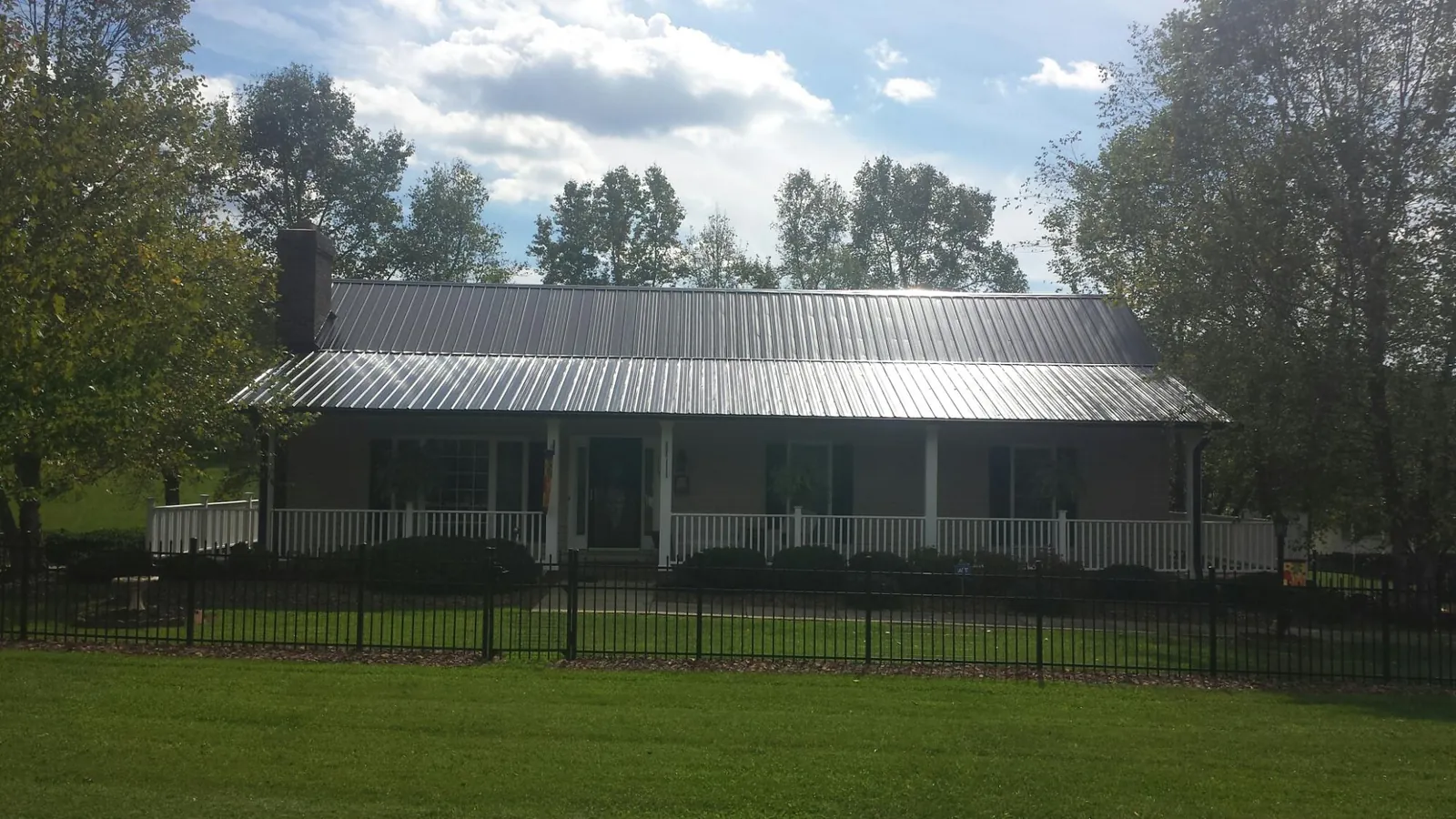 Gray metal roof on a brick ranch with a full width front porch — Gutter Guard Installation work by our crew in Robesonia