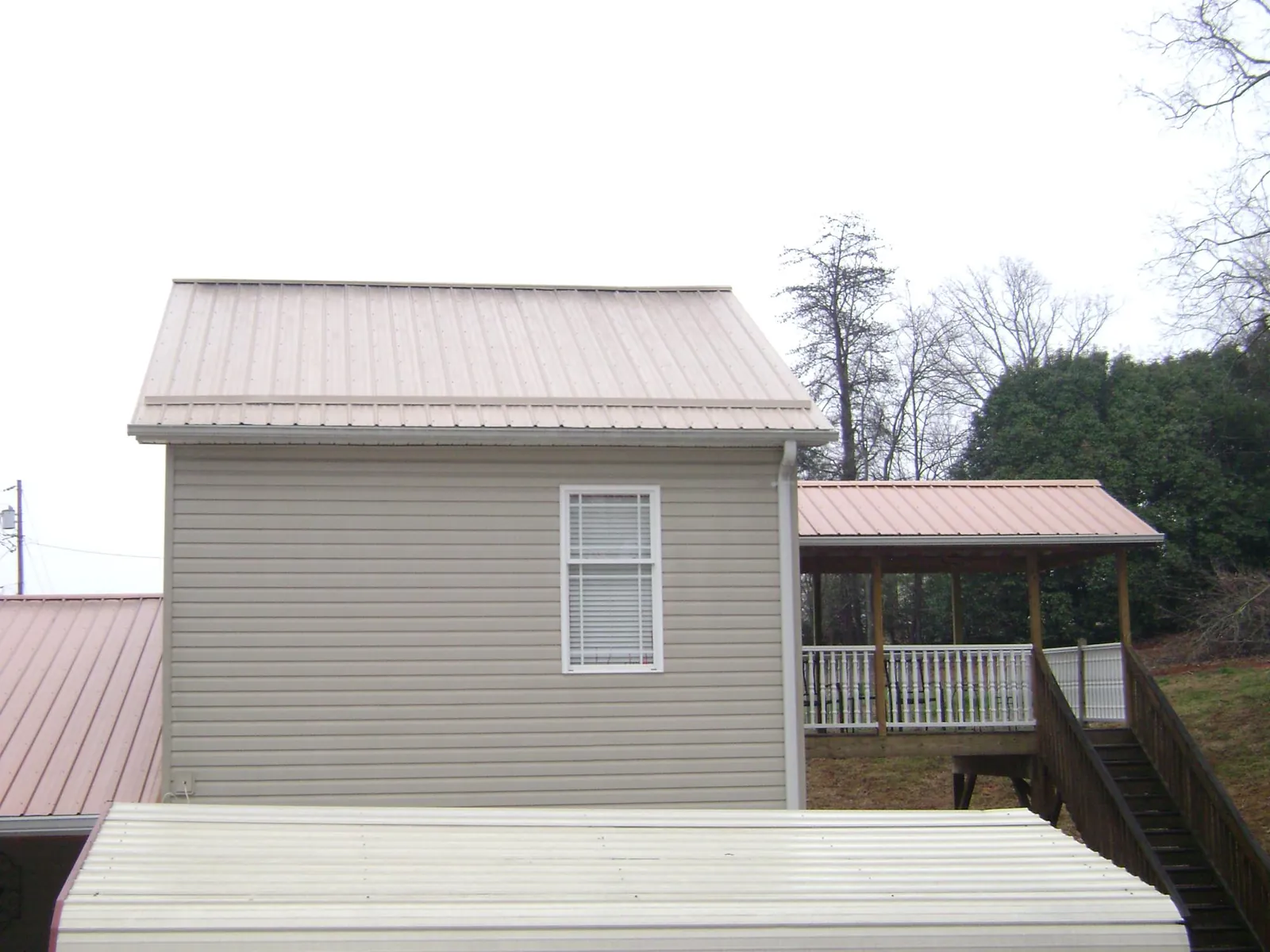 Tan metal roofs on a two story addition and attached porch, from a Roof Replacement job in Robesonia