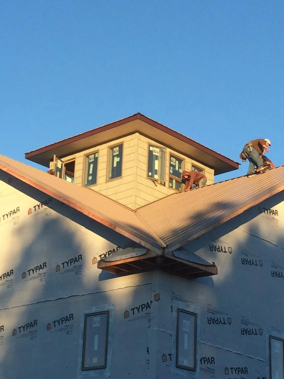 Roofers working around a rooftop cupola on a new metal roof at sunset — Roof Waterproofing in Robesonia by Roofing Brothers